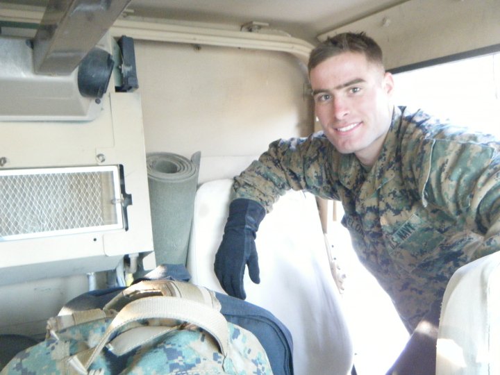 Service member in camo uniform inside the tan interior of an armored military vehicle