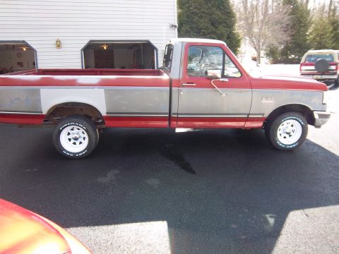 1989 Ford F-150 - This 1989 Ford F-150 pickup truck is shown from the side, a two-tone red and silver paint scheme.