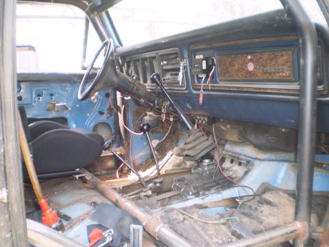 1978 Ford Bronco - The interior shows a roll cage, dual shifters, and a dashboard with wood grain trim and aftermarket gauges.