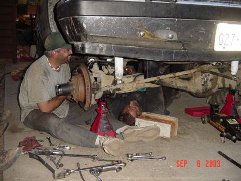 1989 Ford Bronco - Two mechanics are working on the rear axle of a 1989 Ford Bronco.