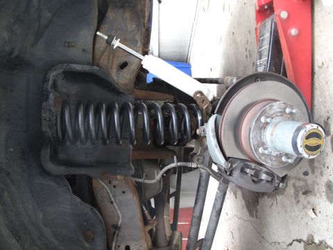 1995 Ford Bronco - Close-up view of the front suspension and brake components, including a coil spring and shock absorber.