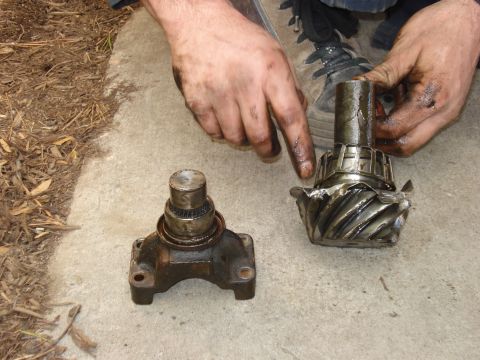 1985 Ford Bronco - Close-up of damaged differential gears and a yoke, with a person's dirty hands holding them.