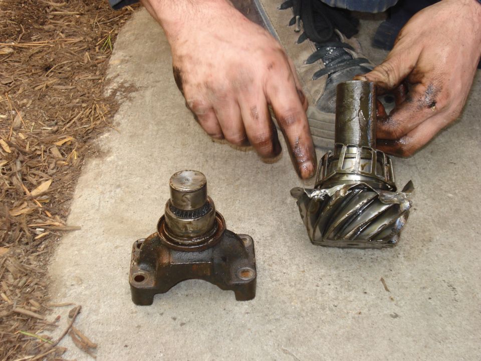 Differential gears and a yoke with bearing, one gear damaged, held by dirty hands