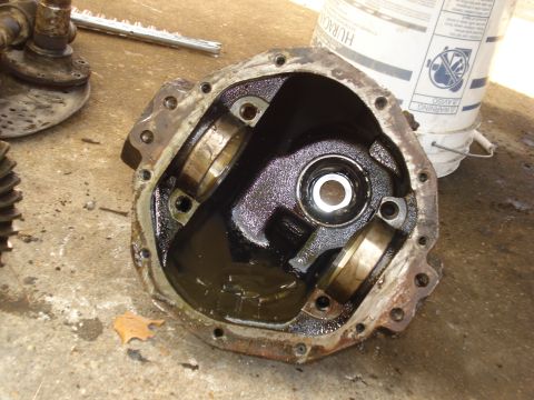 1985 Ford Bronco - A disassembled differential housing sits on a concrete surface, revealing its internal components and oil.