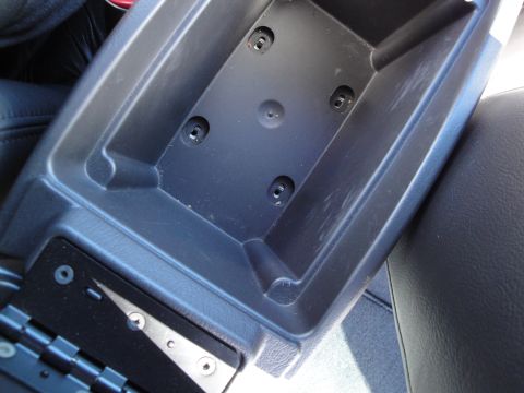 2003 Ford Taurus - Open center console storage bin showing screw mounting points inside.