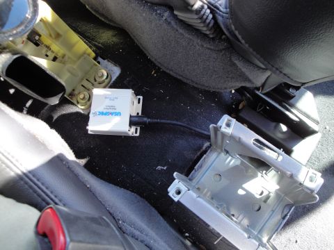 2003 Ford Taurus - USA-SPEC iPod connection kit installed in the interior of a vehicle, near the seat mounting hardware.