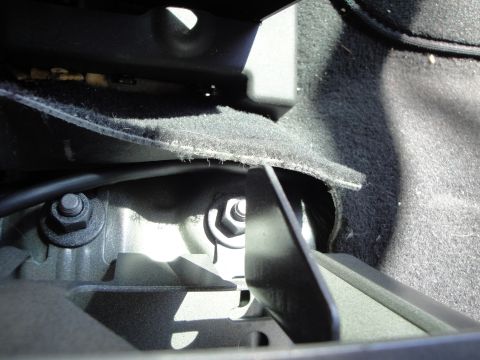 2003 Ford Taurus - Detail of a mounting bracket and wiring harness located beneath the vehicle's seat.