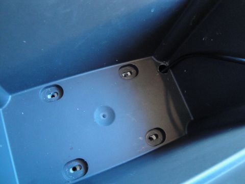 2003 Ford Taurus - Close-up view of a dark blue plastic interior component with visible mounting hardware and a wire pass-through.