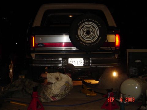 1989 Ford Bronco - A Ford Bronco is being worked on at night, with a spare tire visible on the rear.