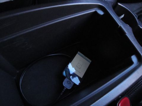 2003 Ford Taurus - An iPod is plugged into a cable inside the dark center console of a vehicle.
