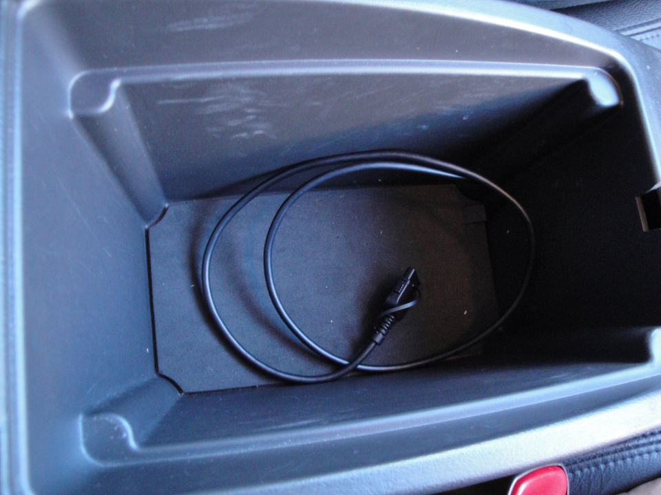 Center console storage bin with a black cable coiled inside