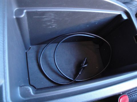 2003 Ford Taurus - The interior storage compartment holds a coiled black cable.