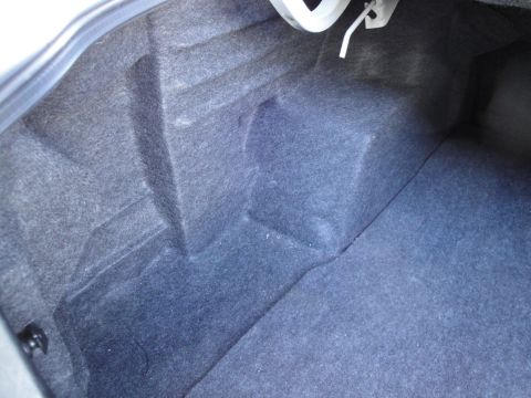 2003 Ford Taurus - The interior of a car trunk is shown, lined with dark grey carpet.