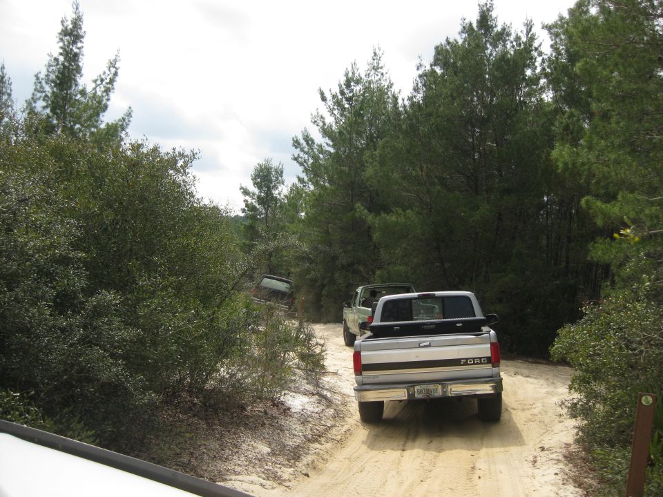 Rear view of a 1994 Ford Bronco driving on a dirt road