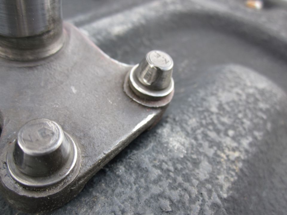 Metal bracket with two bolts, each marked with 'NE'