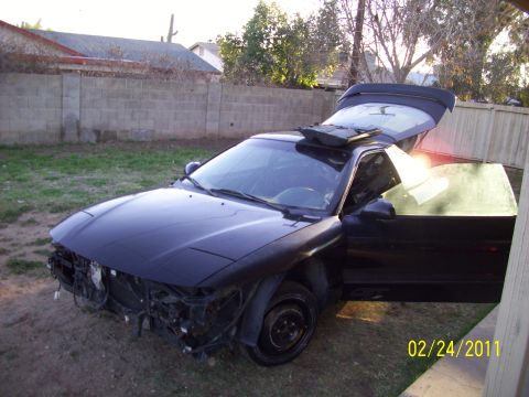 1995 Ford Probe - This black coupe has its front bumper removed and both the driver's door and trunk are open.