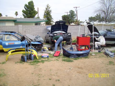 1995 Ford Probe - Several vehicles are being worked on outdoors, with parts and tools scattered around.