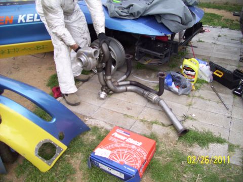 1995 Ford Probe - A person works on a turbocharger next to disassembled car parts and a clutch box.