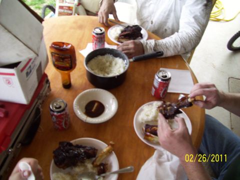 1995 Ford Probe - A meal of ribs and rice is served with soda and BBQ sauce on a wooden table.