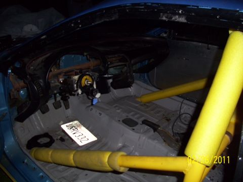 1995 Ford Probe - The interior of a car stripped for racing, a roll cage and exposed dashboard components.