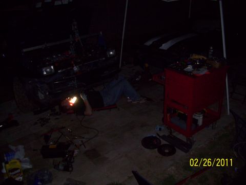 1995 Ford Probe - Mechanic working on the underside of a 1995 Ford Probe at night.