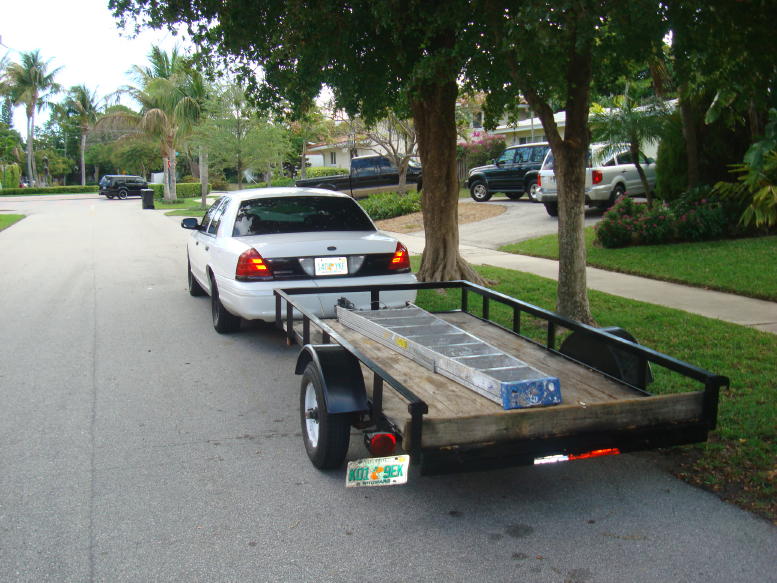 Rear view of a white 2002 Ford Crown Victoria towing a trailer with a ladder