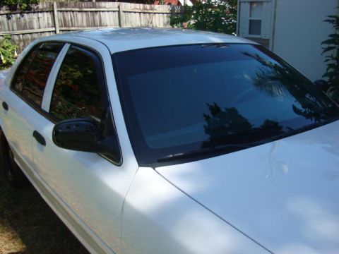 2002 Ford Crown Victoria - The side and front of a white 2002 Ford Crown Victoria with dark tinted windows is shown.