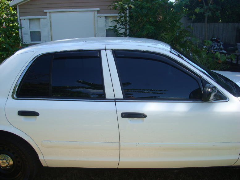 White 2002 Ford Crown Victoria sedan with tinted windows and black door handles, seen from the side