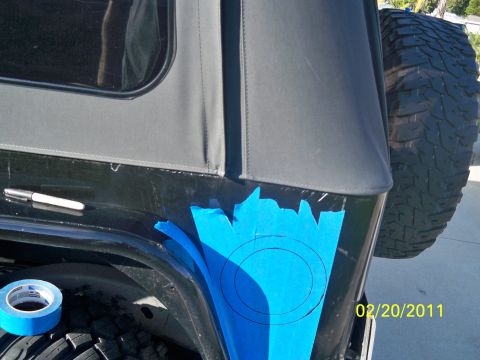 1992 Jeep Wrangler - A black Jeep Wrangler's rear quarter panel is prepped for modification with blue tape and a marker.