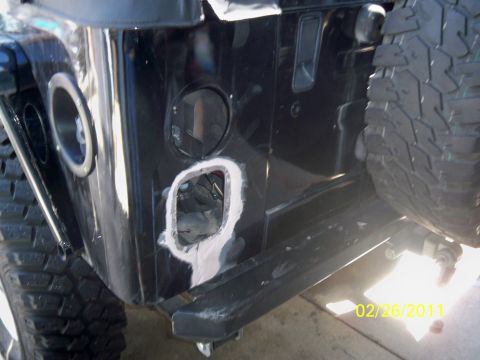 1992 Jeep Wrangler - The rear bumper area of a black Jeep Wrangler shows bodywork being done around a removed taillight assembly.