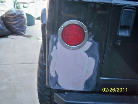 1992 Jeep Wrangler - Body filler is applied to the rear quarter panel of a Jeep Wrangler around the tail light assembly.