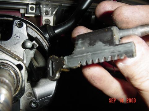 1989 Ford Bronco - A hand holds a damaged ignition switch actuator, showing the worn teeth and a broken section.
