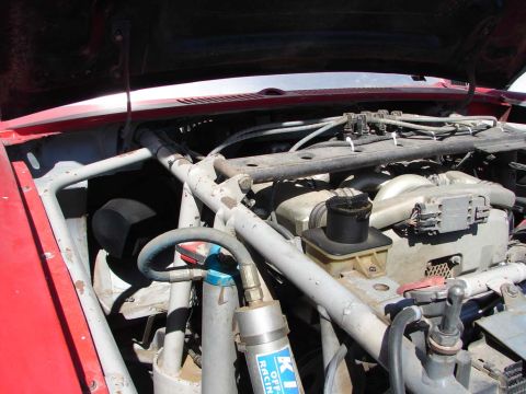 1992 Ford Taurus - Engine bay of a red vehicle, modified with a roll cage and racing components, is shown from a high angle.