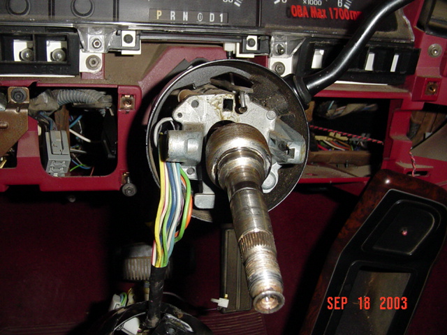 Exposed steering column shaft and wiring on a burgundy dash interior