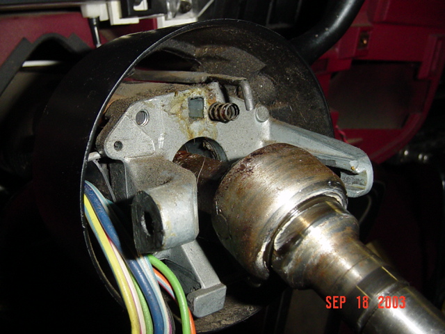 Disassembled steering column ignition switch with spring, shaft, and colored wire bundle