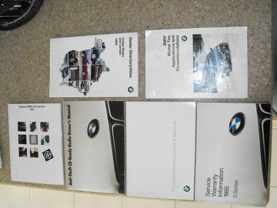 Several BMW manuals and a 1994 accessories catalog laid out on a floor