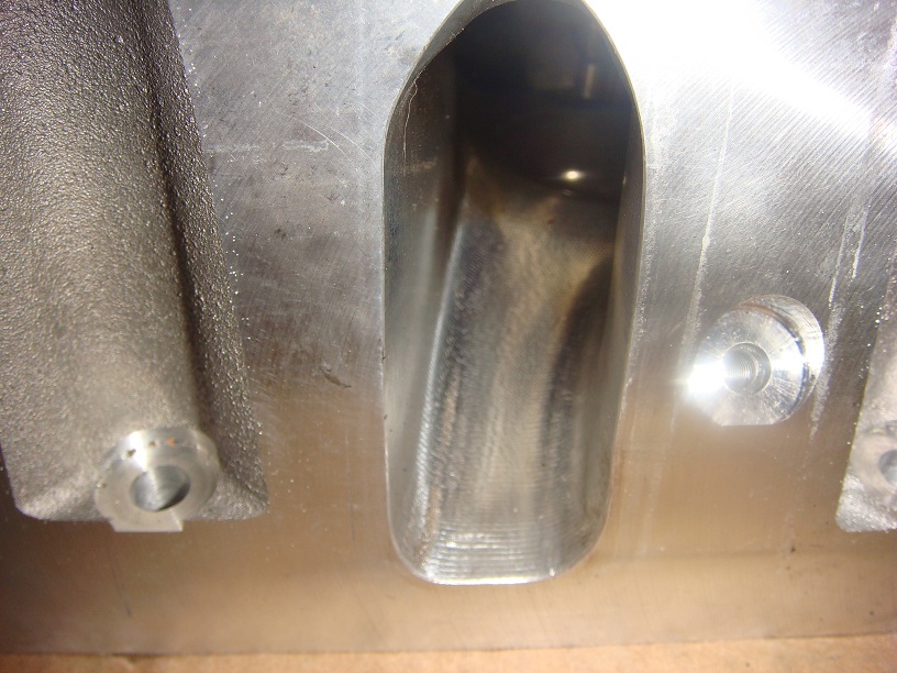 Close-up of a machined metal engine intake port with visible machining marks