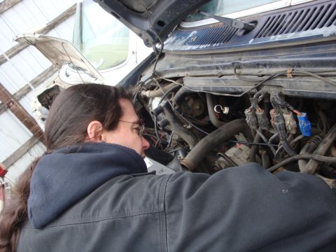 1989 Ford Bronco - A person is focused on working on the complex engine of a vehicle, with the hood open.