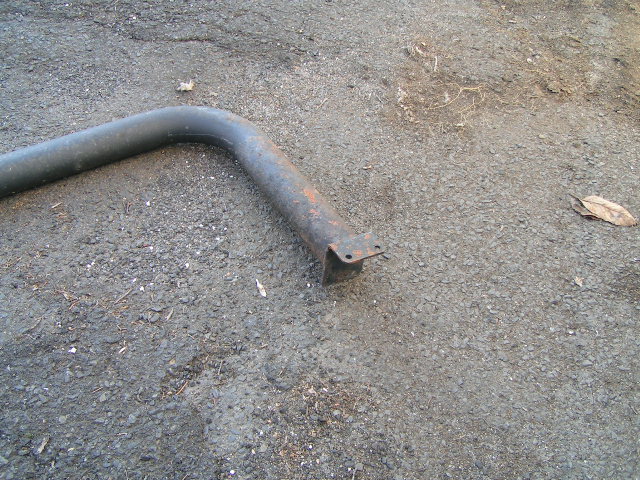 rusted metal pipe with mounting bracket on asphalt