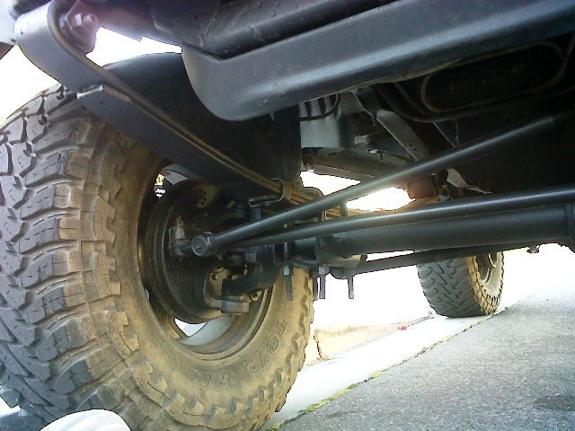 Undercarriage view of a vehicle's rear axle and suspension with large off-road tires