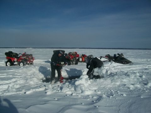 1986 Chevrolet Blazer - Several ATVs and snowmobiles are parked on a frozen lake as people ice fish.
