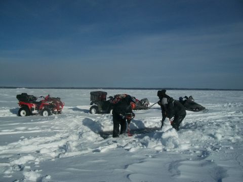 1986 Chevrolet Blazer - Several people are ice fishing on a frozen body of water, with ATVs and snowmobiles parked in the snow.