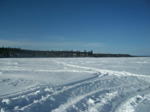 1986 Chevrolet Blazer - A vast, snow-covered landscape with tracks suggesting recent activity, under a clear blue sky.