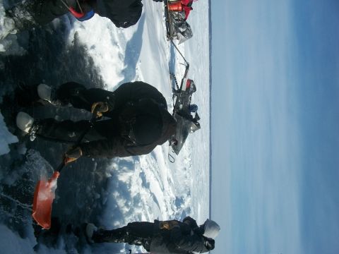 1986 Chevrolet Blazer - People and a snowmobile are on a frozen body of water under a clear blue sky. The Supermotors.net logo is visible in the lower right corner.
