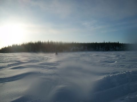 1986 Chevrolet Blazer - A snowmobile travels across a vast, snow-covered expanse under a hazy sky.
