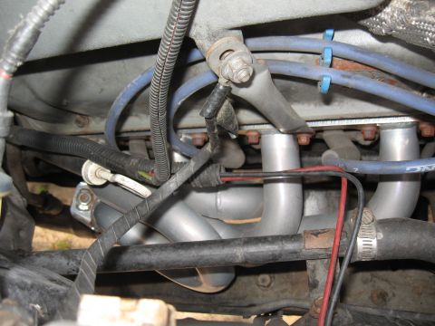 1994 Ford Bronco - Close-up view of engine exhaust headers, likely an aftermarket part, with associated wiring and hoses.
