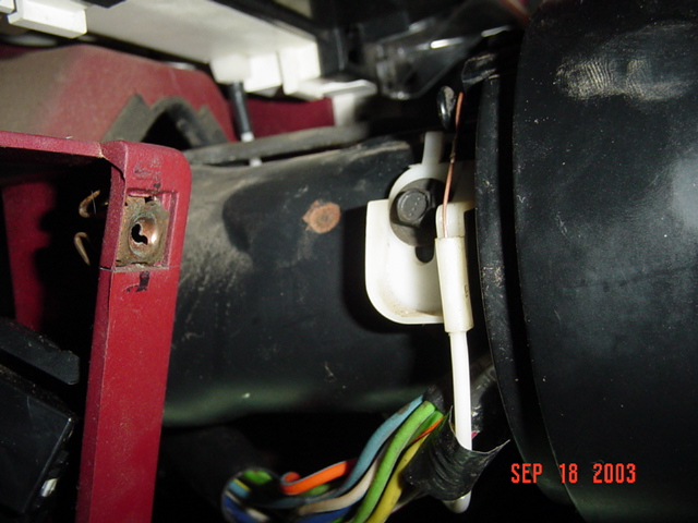 Under-dash view of black bracket, white connector and colorful wiring harness