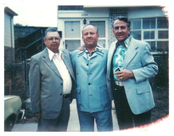 Three men in suits standing in front of a house