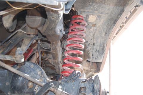 1982 Ford Bronco - Close-up of vehicle suspension components, including a red coil spring, with a watermark at the bottom right.