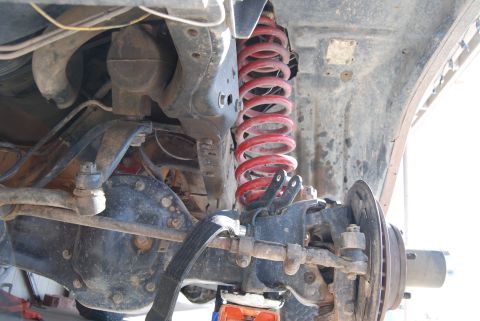 1982 Ford Bronco - Close-up view of the front suspension and differential assembly, showing the red coil spring and suspension components.